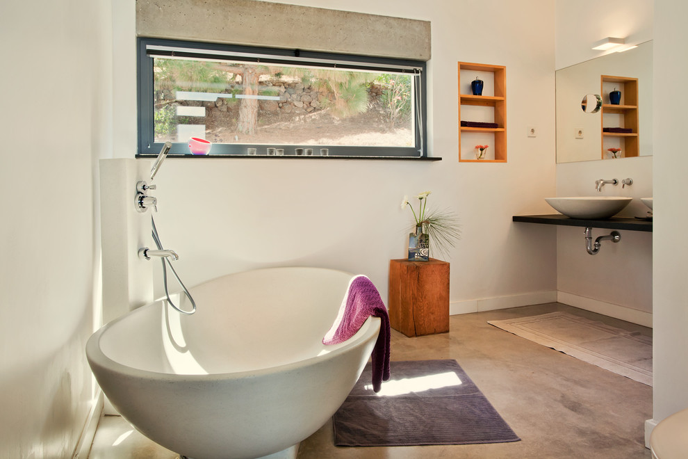 Idéer för att renovera ett mellanstort funkis en-suite badrum, med öppna hyllor, skåp i mellenmörkt trä, ett fristående badkar, en dusch/badkar-kombination, vita väggar, betonggolv och ett fristående handfat