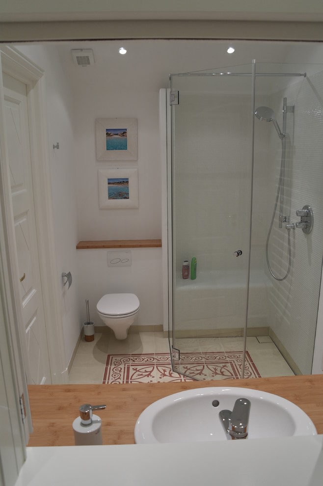 Example of a small tuscan 3/4 white tile ceramic tile and multicolored floor corner shower design in Hamburg with a two-piece toilet, white walls, a drop-in sink, wood countertops, a hinged shower door and brown countertops