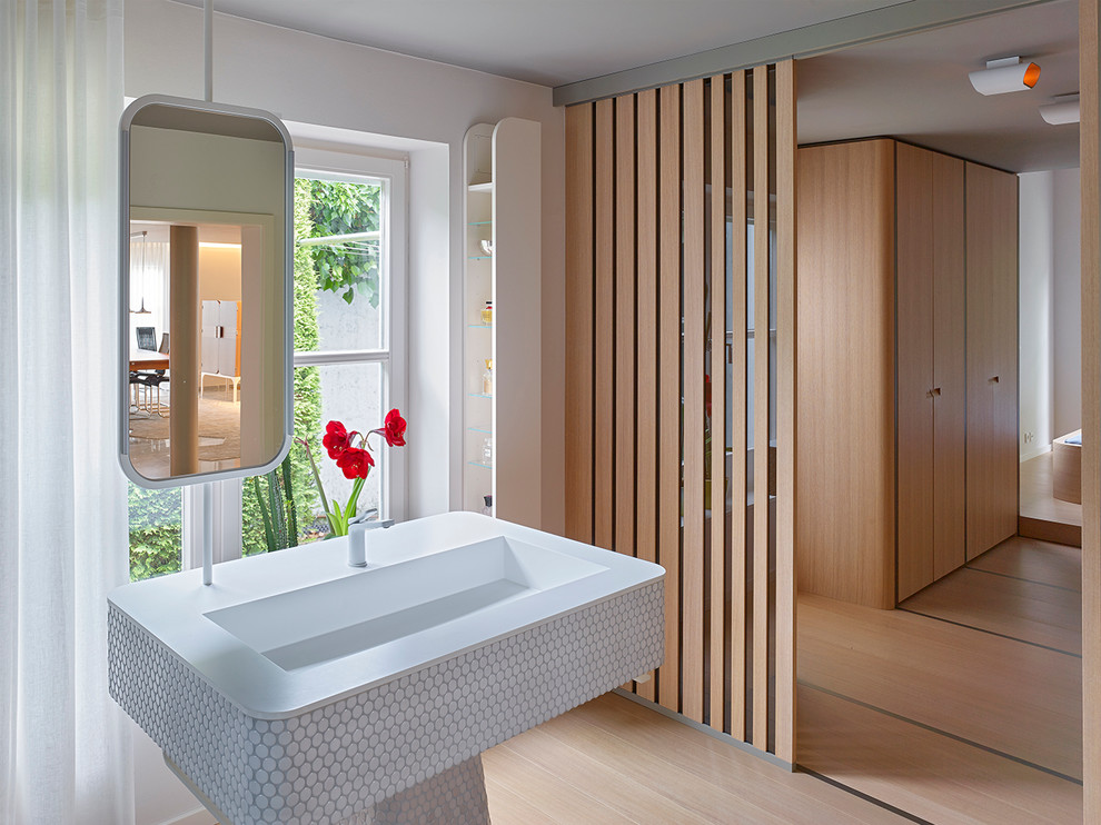 Foto di una stanza da bagno minimal con pareti bianche, pavimento in legno massello medio e lavabo integrato