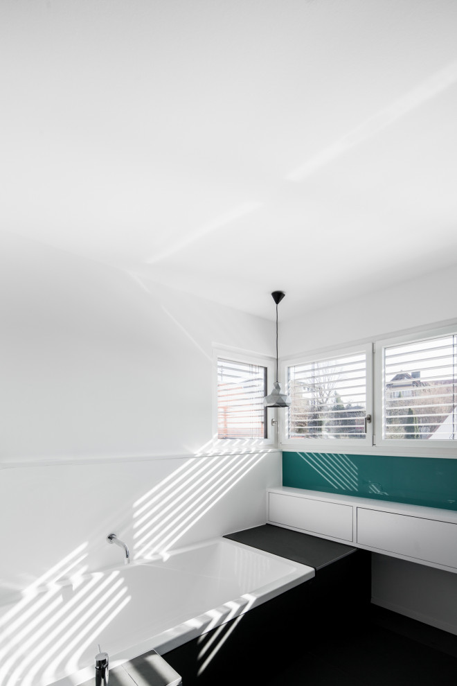 Mittelgroßes Modernes Badezimmer En Suite mit flächenbündigen Schrankfronten, weißen Schränken, Einbaubadewanne, weißer Wandfarbe, Schieferboden und schwarzem Boden in München