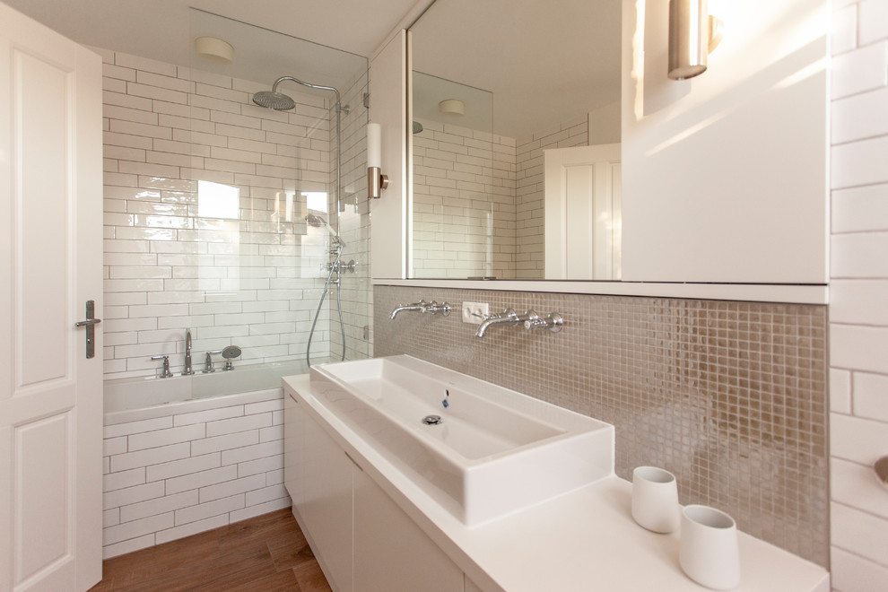 ベルリンにあるラグジュアリーな広いコンテンポラリースタイルのおしゃれな浴室 (ドロップイン型浴槽、ベージュのタイル、ガラスタイル、白い壁、淡色無垢フローリング、ベッセル式洗面器、白い洗面カウンター) の写真