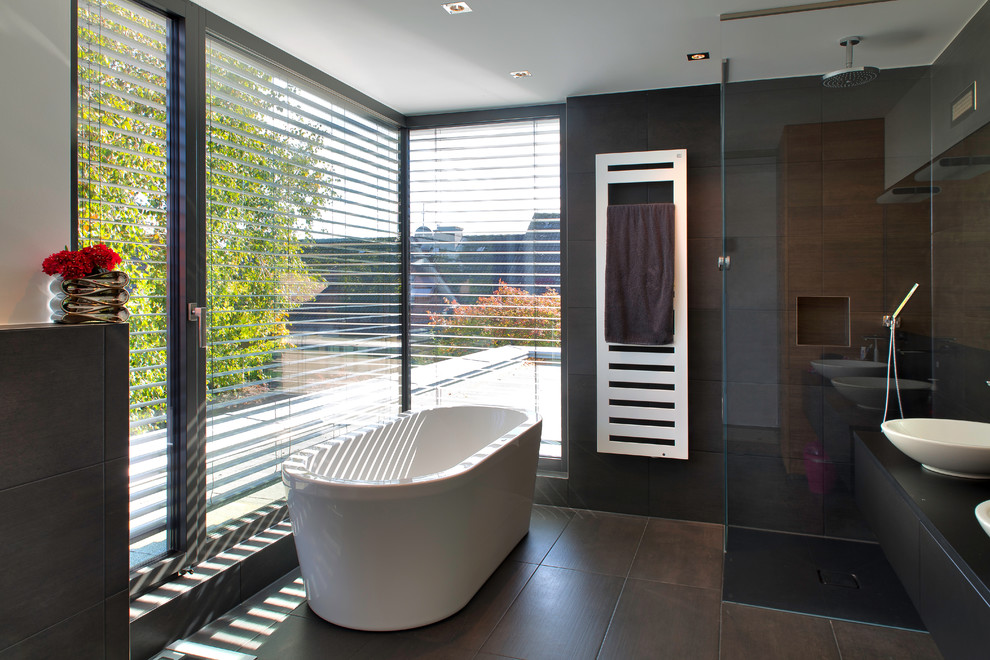На фото: ванная комната среднего размера в стиле модернизм с настольной раковиной, черными фасадами, отдельно стоящей ванной, угловым душем, коричневой плиткой, белыми стенами и плоскими фасадами