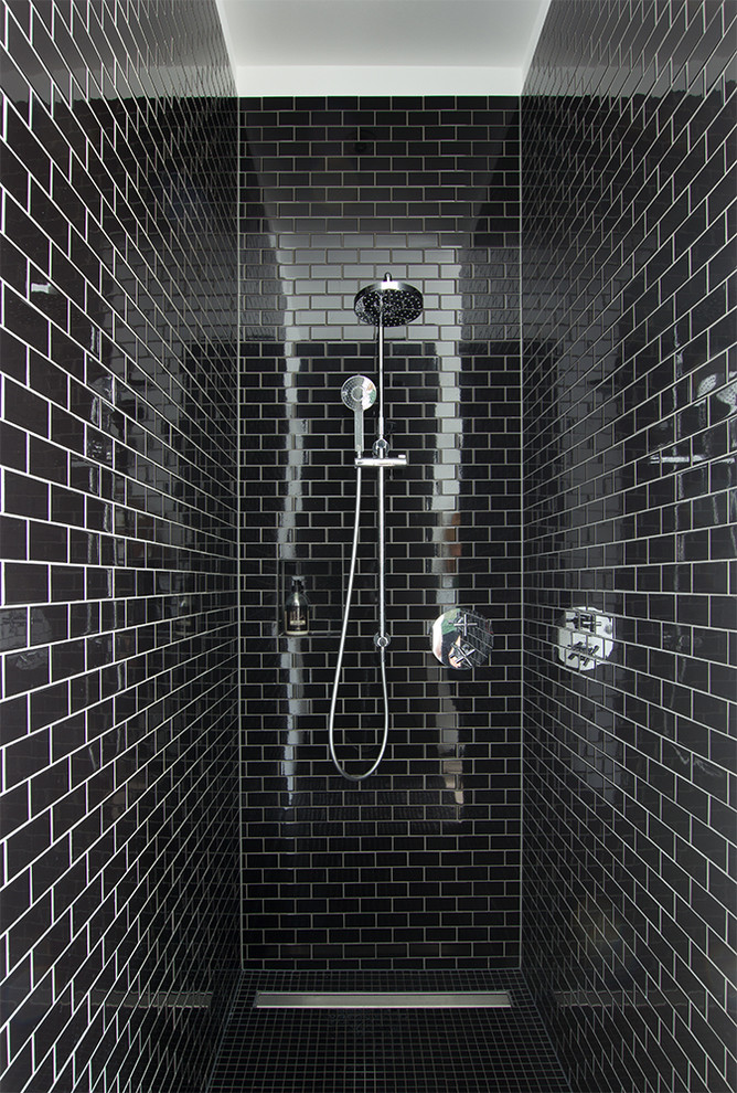 Idéer för mellanstora industriella badrum med dusch, med släta luckor, svarta skåp, en kantlös dusch, en vägghängd toalettstol, svart kakel, porslinskakel, svarta väggar, ljust trägolv, ett fristående handfat, bänkskiva i akrylsten, beiget golv och med dusch som är öppen