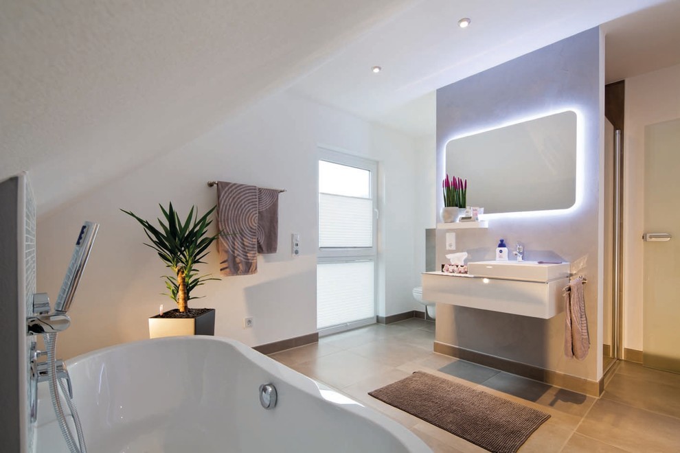 Foto på ett funkis vit badrum, med vita skåp, ett fristående badkar, en kantlös dusch, en vägghängd toalettstol, vita väggar, klinkergolv i terrakotta, ett väggmonterat handfat och grått golv