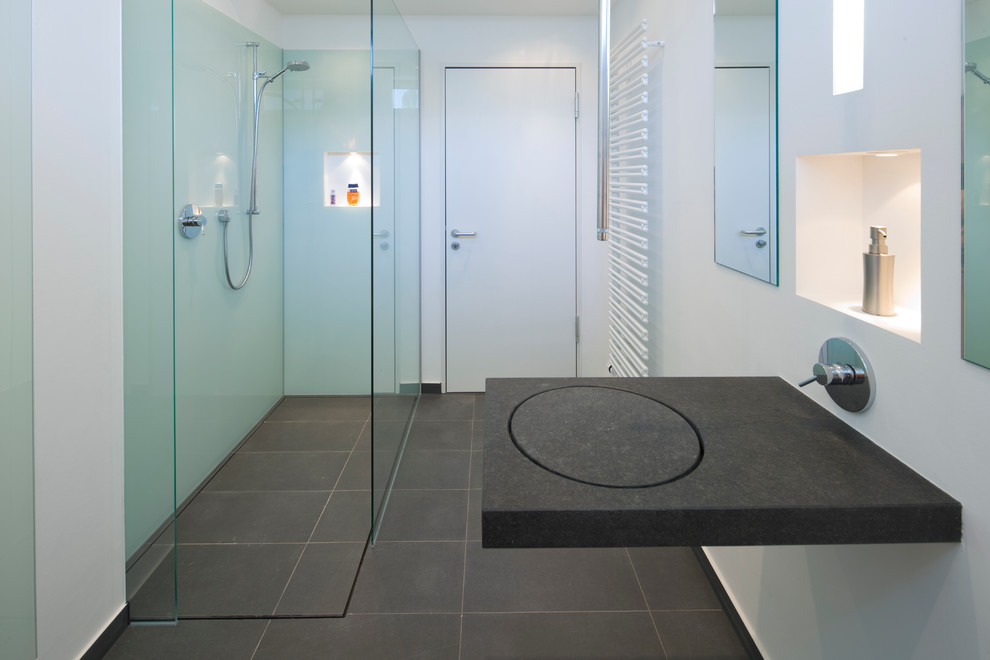 Foto de cuarto de baño actual de tamaño medio con ducha a ras de suelo, baldosas y/o azulejos grises, paredes blancas, aseo y ducha y encimera de granito