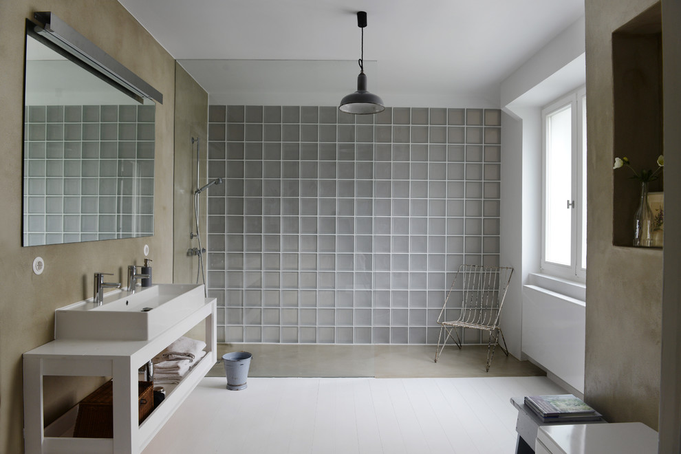 Industriell inredning av ett stort vit vitt badrum, med öppna hyllor, vita skåp, vita väggar, målat trägolv, ett avlångt handfat, träbänkskiva och en kantlös dusch
