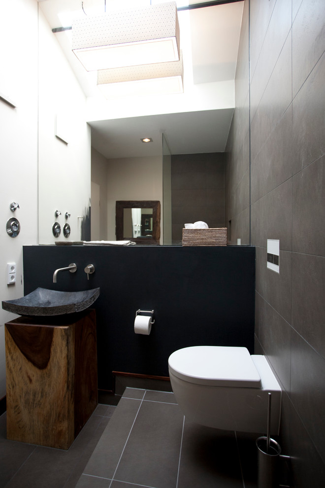 Immagine di una stanza da bagno con doccia etnica con top in legno, doccia aperta, lavabo a bacinella, WC sospeso e pareti marroni