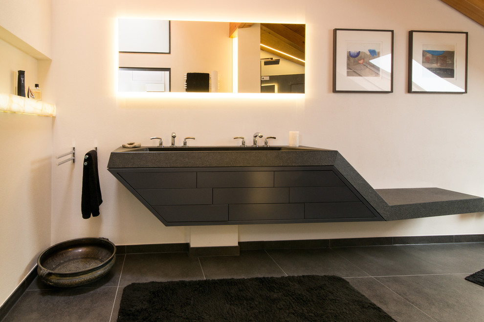 На фото: большая ванная комната в современном стиле с раковиной с несколькими смесителями, белыми стенами, плоскими фасадами, черными фасадами и полом из сланца