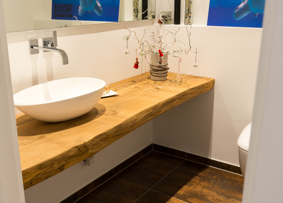 Ejemplo de cuarto de baño rústico con paredes blancas, suelo de baldosas de cerámica, lavabo sobreencimera, encimera de madera y suelo multicolor