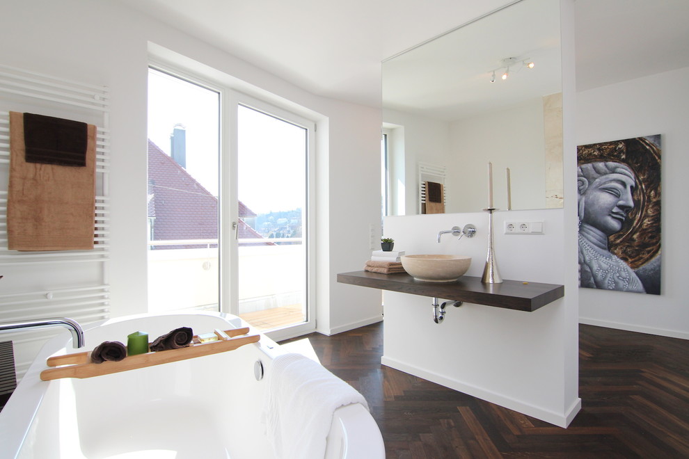 Medium sized contemporary ensuite bathroom in Stuttgart with a vessel sink, white walls, dark hardwood flooring, wooden worktops, a freestanding bath and brown tiles.