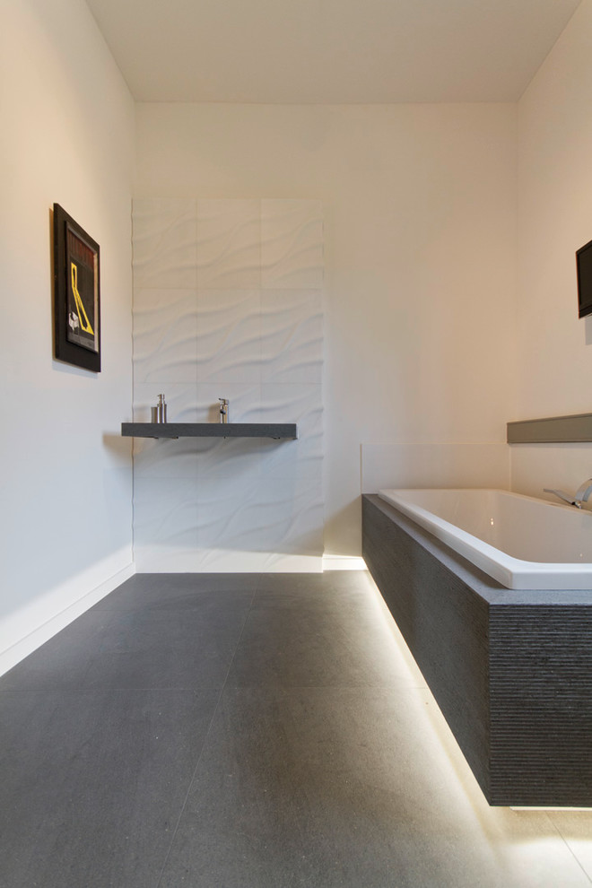 Cette image montre une salle de bain design de taille moyenne avec un carrelage blanc, un mur blanc, un lavabo posé et une baignoire posée.