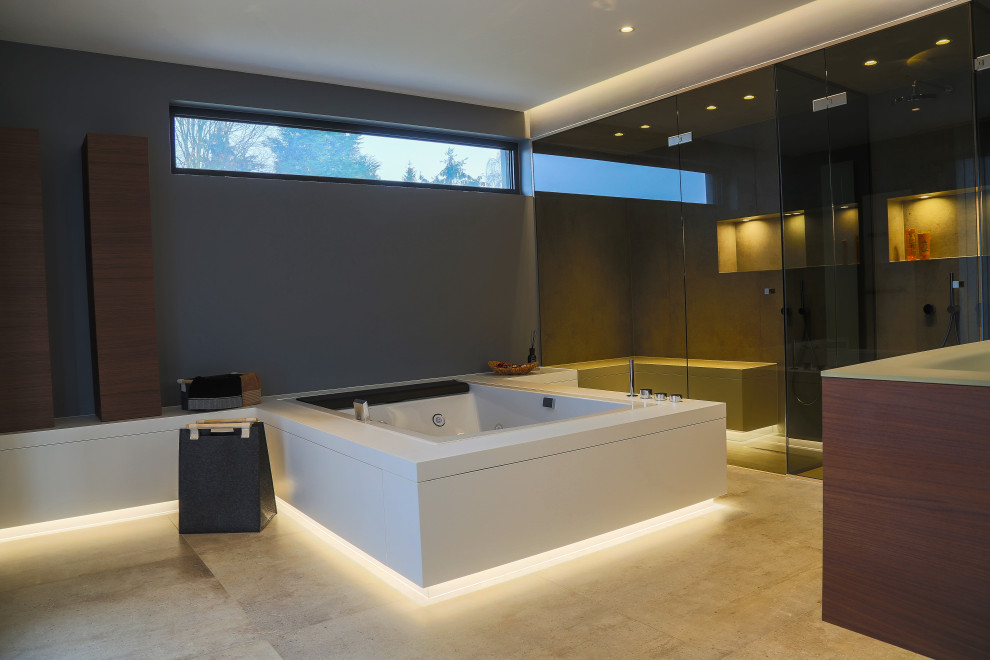 Photo of a large modern ensuite bathroom in Frankfurt with flat-panel cabinets, dark wood cabinets, a built-in bath, a built-in shower, a wall mounted toilet, grey tiles, stone tiles, grey walls, cement flooring, an integrated sink, glass worktops, beige floors, an open shower, green worktops, a shower bench, double sinks, a floating vanity unit, a drop ceiling and wainscoting.