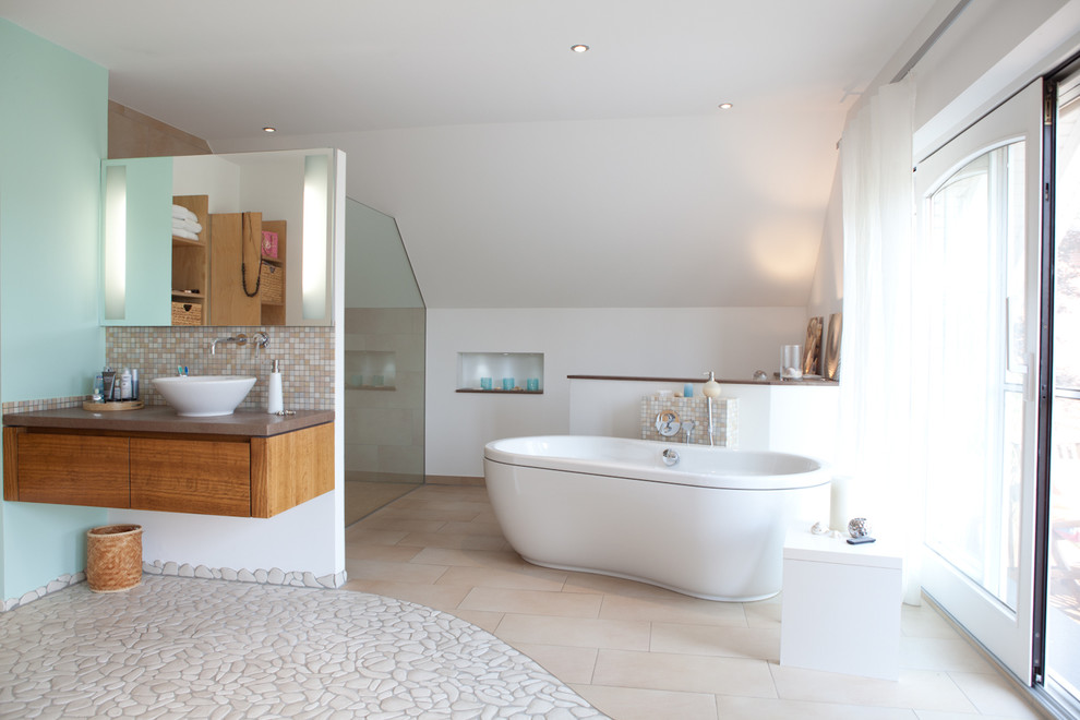 Idéer för ett mycket stort modernt badrum, med släta luckor, skåp i mellenmörkt trä, ett fristående badkar, en dusch i en alkov, beige kakel, vit kakel, mosaik, vita väggar, klinkergolv i småsten och ett fristående handfat