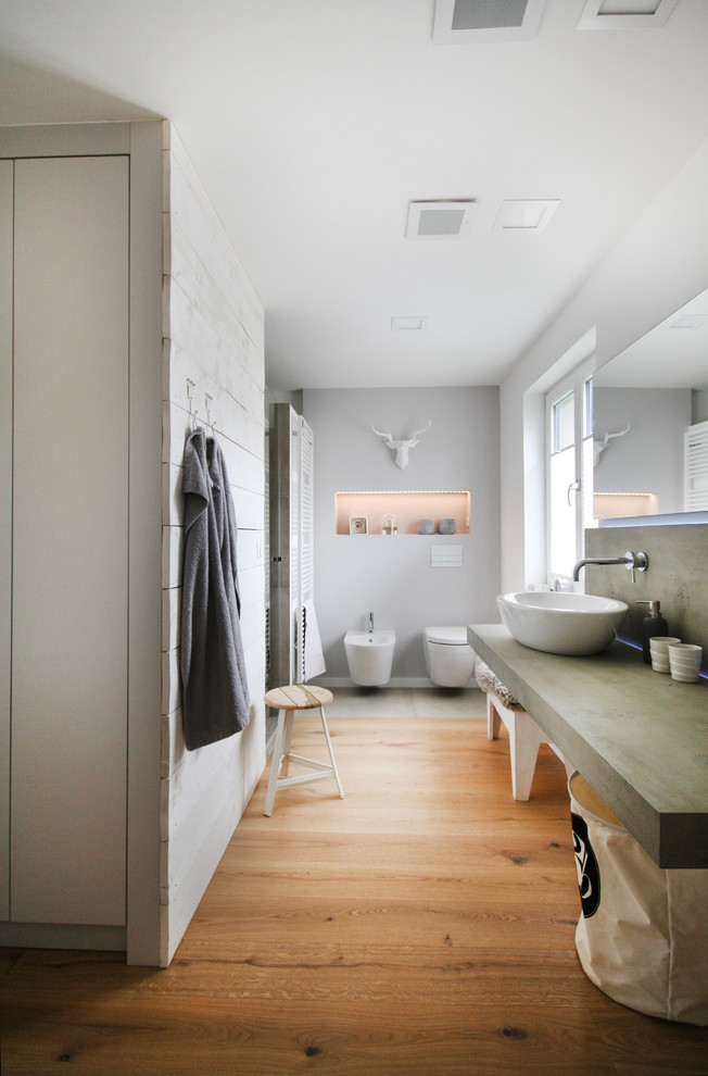 Пример оригинального дизайна: большая ванная комната в скандинавском стиле с биде, серыми стенами, паркетным полом среднего тона, настольной раковиной, столешницей из бетона и окном