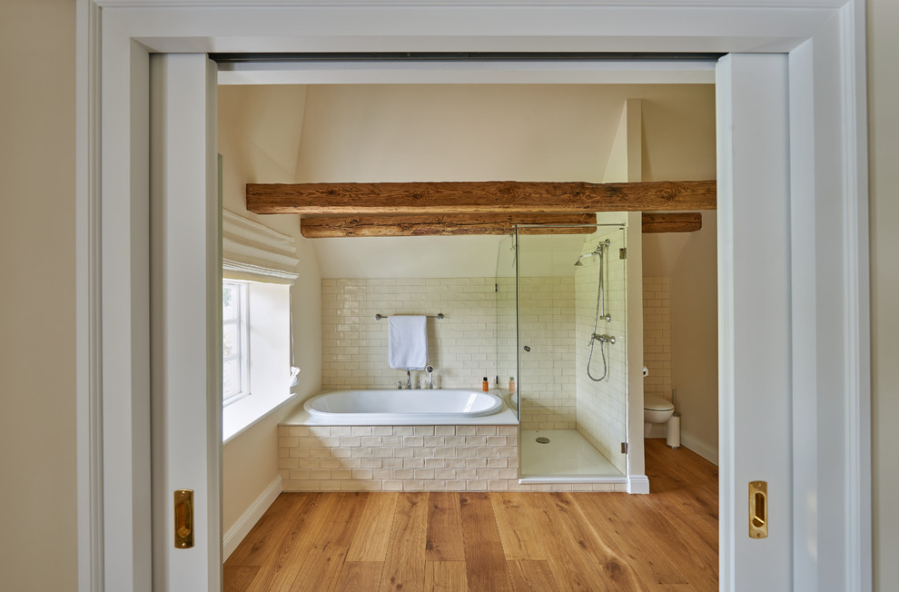 Aménagement d'une salle de bain montagne de taille moyenne avec une baignoire posée, une douche d'angle, WC suspendus, un carrelage beige, un carrelage métro, un mur jaune, un sol en bois brun et une cabine de douche à porte battante.