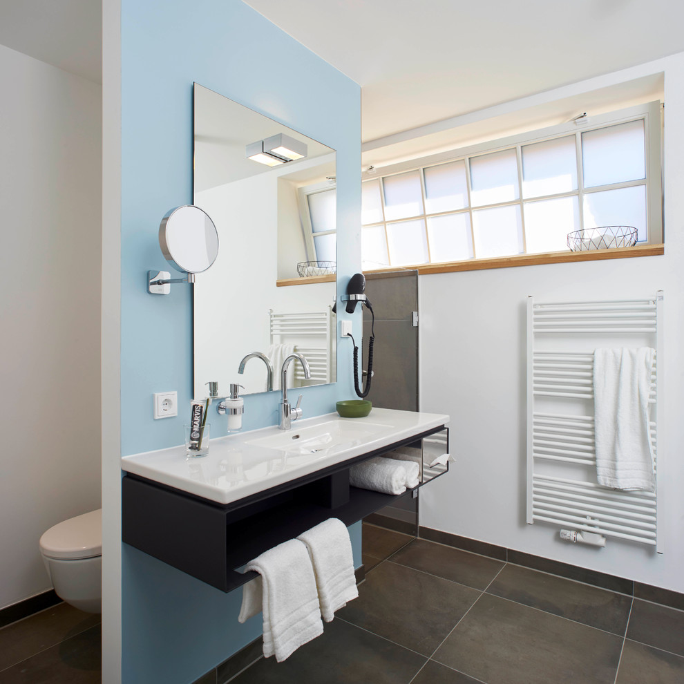 Bild på ett mellanstort funkis badrum med dusch, med öppna hyllor, svarta skåp, blå väggar och ett integrerad handfat