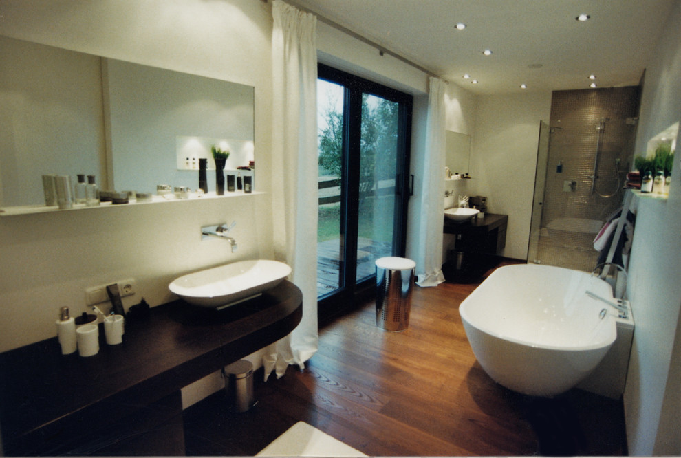 Immagine di una stanza da bagno padronale contemporanea di medie dimensioni con vasca freestanding, doccia a filo pavimento, parquet scuro, top in legno, pavimento marrone e porta doccia scorrevole