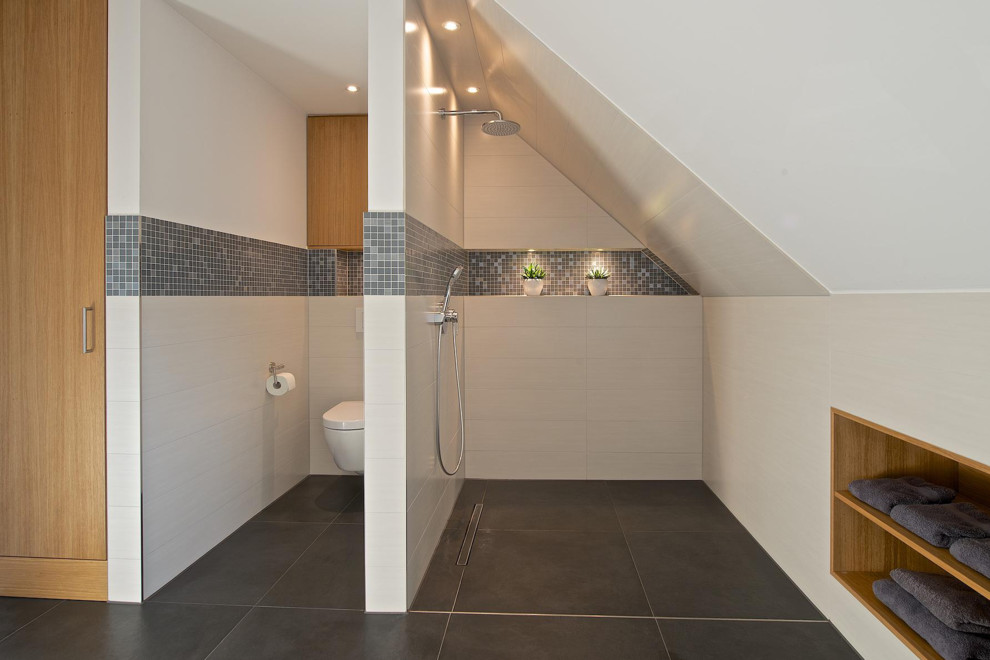 Bild på ett stort funkis badrum, med skåp i ljust trä, vit kakel, keramikplattor, vita väggar, öppna hyllor, en vägghängd toalettstol, skiffergolv och en kantlös dusch