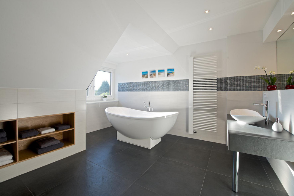 Источник вдохновения для домашнего уюта: огромная ванная комната с настольной раковиной, светлыми деревянными фасадами, отдельно стоящей ванной, белыми стенами, полом из сланца, белой плиткой, керамической плиткой и окном