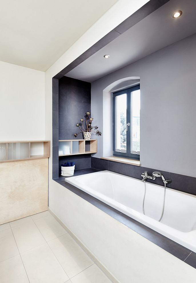 Ejemplo de cuarto de baño rectangular contemporáneo con baldosas y/o azulejos grises, armarios abiertos, puertas de armario de madera oscura, bañera empotrada y paredes blancas