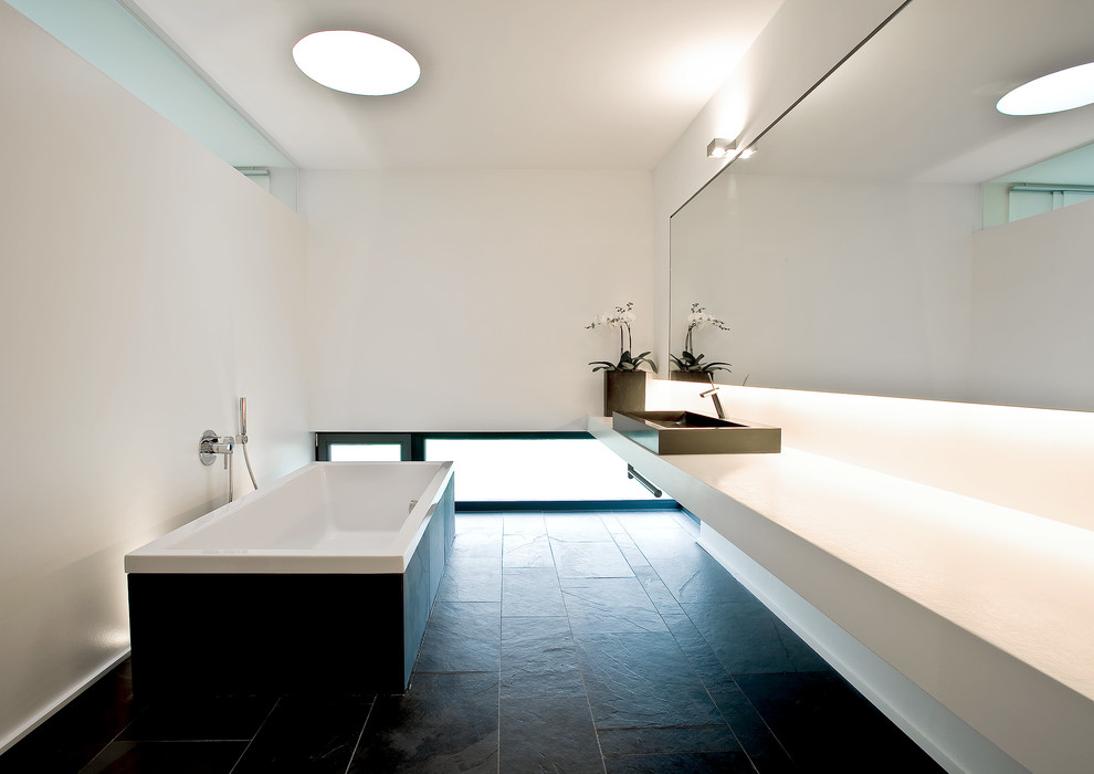 Свежая идея для дизайна: большая ванная комната в стиле модернизм с настольной раковиной, белыми стенами, отдельно стоящей ванной, черной плиткой, плиткой из листового камня и полом из сланца - отличное фото интерьера