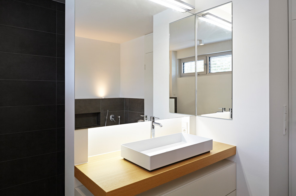Modernes Badezimmer mit Aufsatzwaschbecken, Waschtisch aus Holz, grauen Fliesen und weißer Wandfarbe in Frankfurt am Main