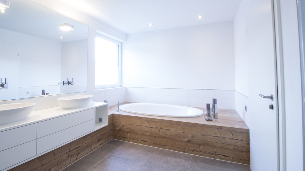 Photo of a large contemporary bathroom in Nuremberg with flat-panel cabinets, white cabinets, a submerged bath, white walls and a vessel sink.
