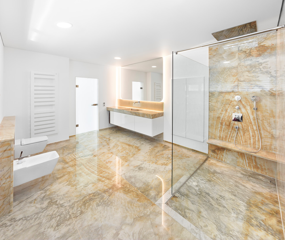 Imagen de cuarto de baño actual con puertas de armario blancas, ducha a ras de suelo, sanitario de pared, paredes blancas, lavabo suspendido y encimera de cuarcita