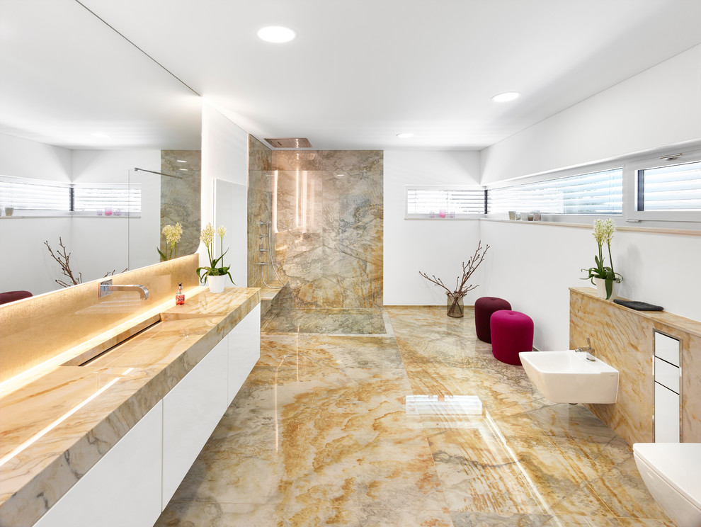 Bild på ett funkis badrum med dusch, med vita skåp, en kantlös dusch, en vägghängd toalettstol, glaskakel, vita väggar, ett väggmonterat handfat och bänkskiva i kvartsit