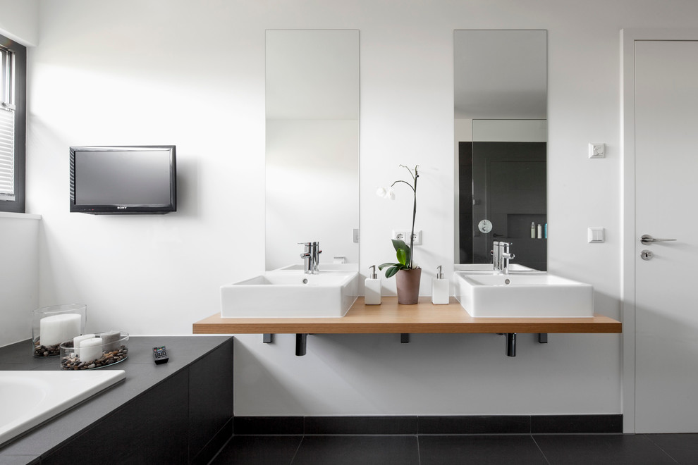 Cette photo montre une grande salle de bain tendance avec une vasque, une baignoire posée, un mur blanc, un sol en ardoise et un plan de toilette en bois.