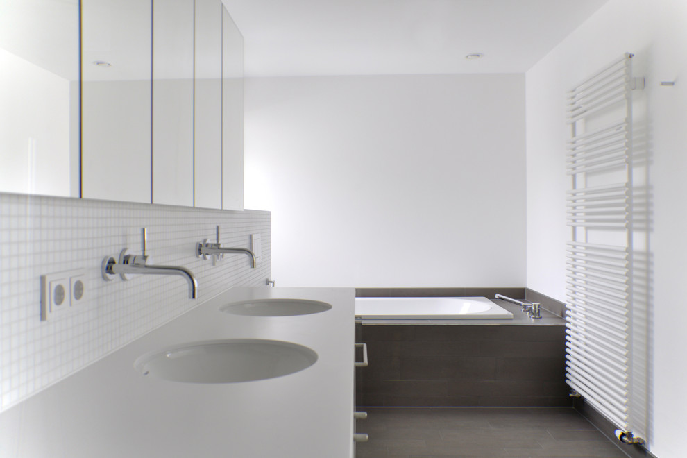 Foto di una stanza da bagno minimal di medie dimensioni con vasca da incasso, piastrelle bianche, piastrelle a mosaico, pareti bianche e lavabo sottopiano