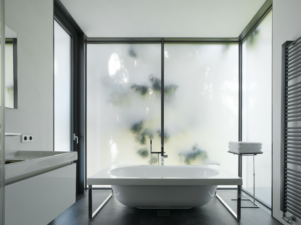 Diseño de cuarto de baño minimalista grande con bañera exenta, armarios con paneles lisos, puertas de armario blancas y paredes blancas