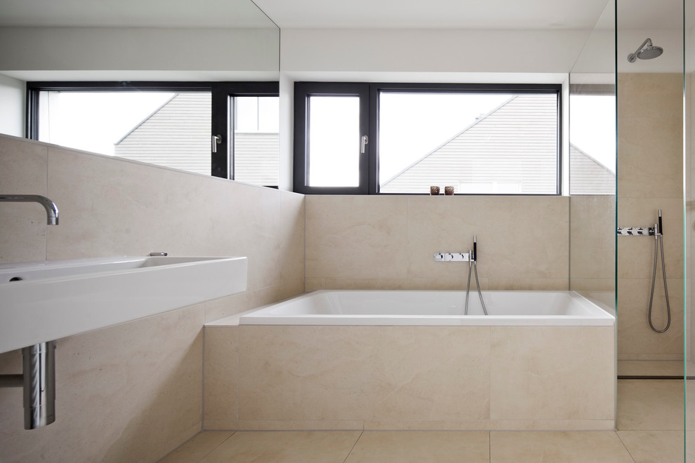 Imagen de cuarto de baño beige y blanco moderno grande con lavabo suspendido, ducha esquinera, baldosas y/o azulejos beige, paredes beige, bañera empotrada, baldosas y/o azulejos de piedra y suelo de piedra caliza