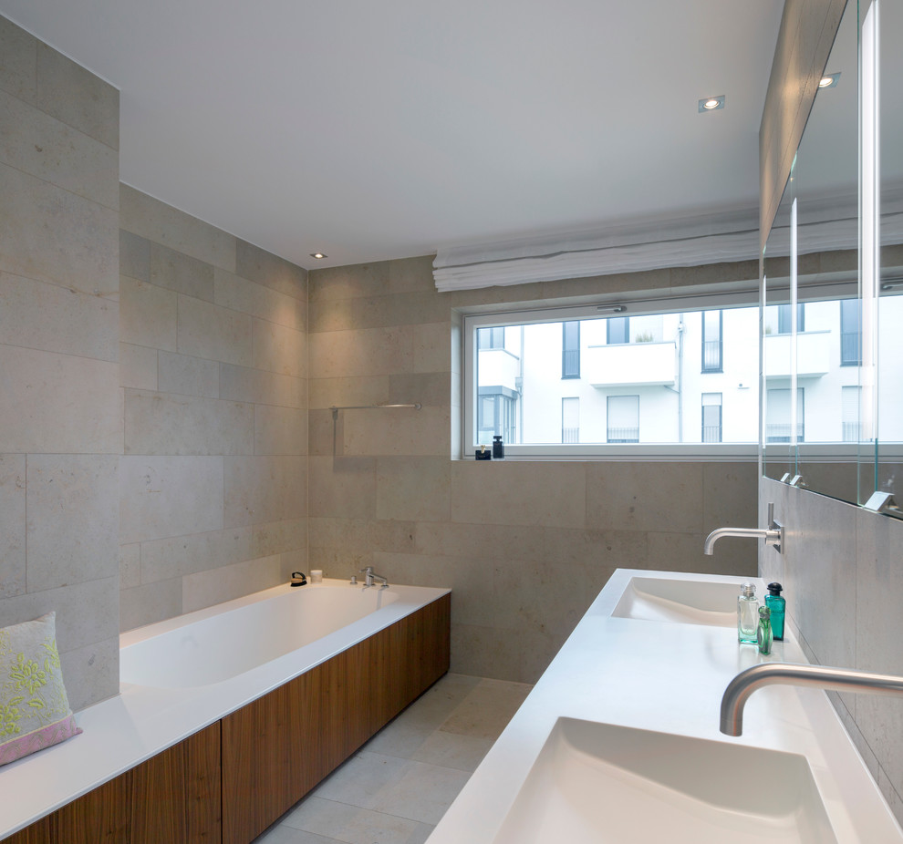Imagen de cuarto de baño doble actual de tamaño medio con bañera encastrada, lavabo integrado, suelo gris y encimeras blancas