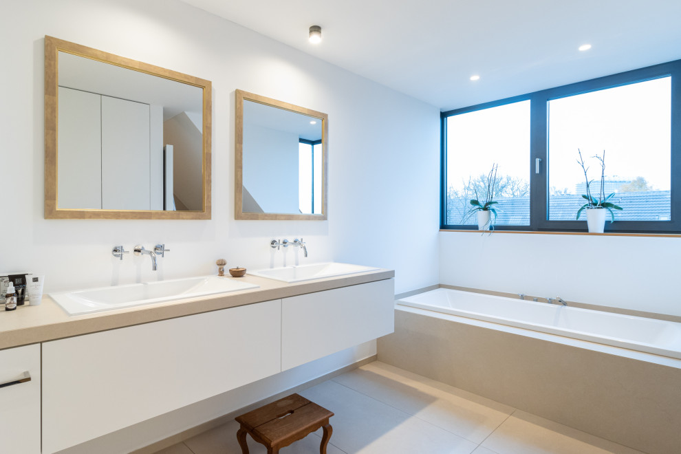 Modernes Badezimmer mit flächenbündigen Schrankfronten, Einbaubadewanne, Doppelwaschbecken und eingebautem Waschtisch in Köln