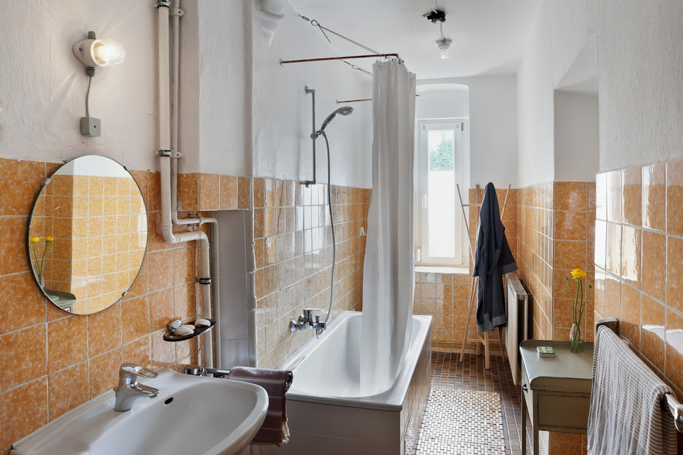 Cette image montre une salle de bain traditionnelle de taille moyenne avec une baignoire encastrée, un combiné douche/baignoire, un carrelage orange, des carreaux de céramique, un mur orange, un sol en carrelage de céramique et un lavabo suspendu.