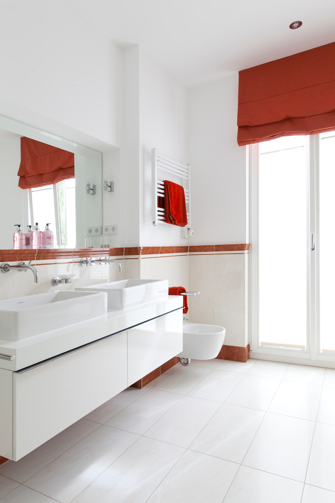 Cette photo montre une grande salle de bain tendance avec un mur blanc, une vasque, un placard à porte plane, des portes de placard blanches, un bidet et un carrelage beige.