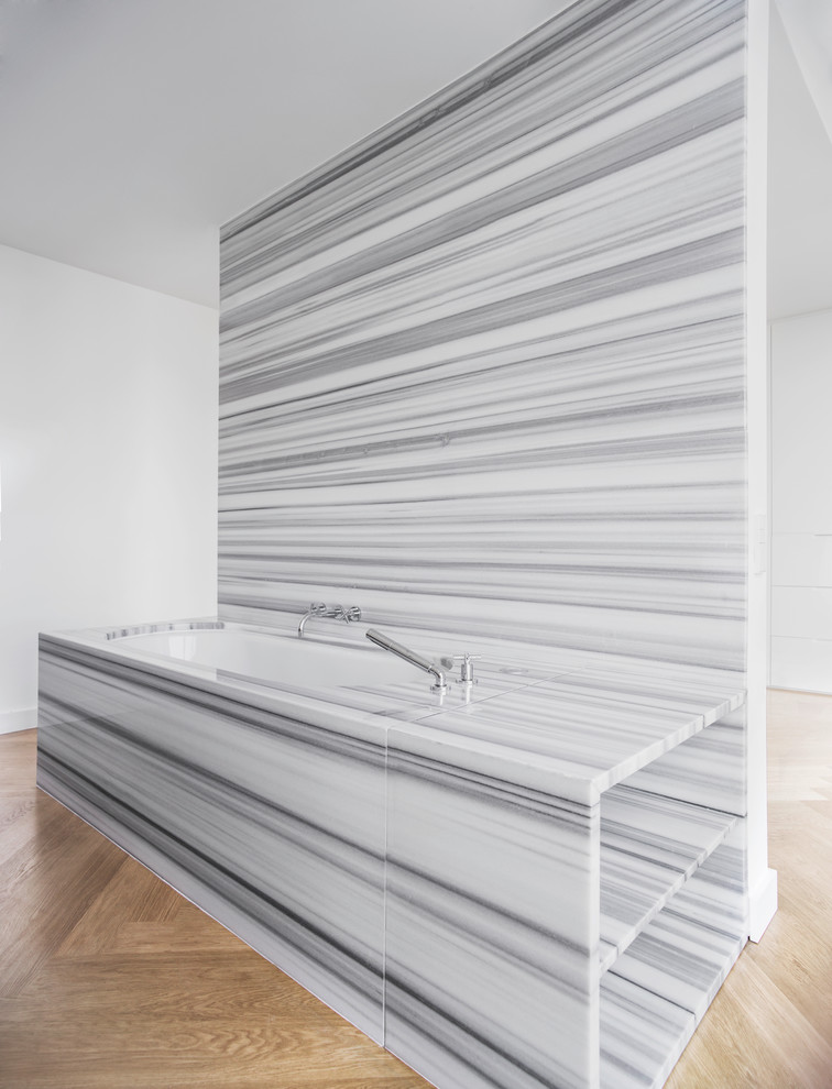 Bild på ett funkis en-suite badrum, med ett undermonterat badkar, stenhäll, vita väggar och mellanmörkt trägolv