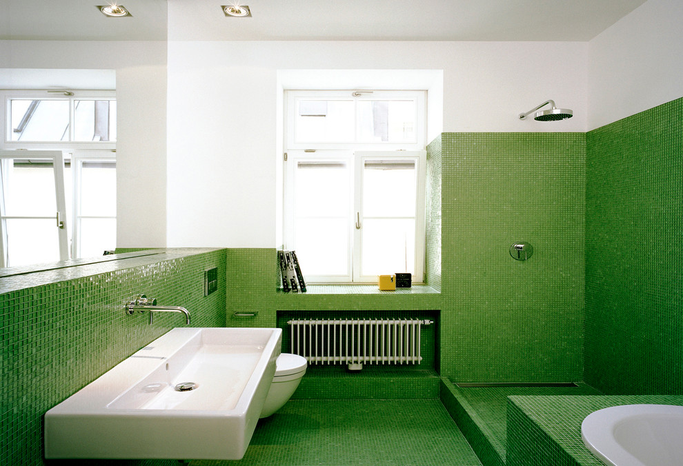 Modern inredning av ett mellanstort badrum, med ett platsbyggt badkar, en öppen dusch, en vägghängd toalettstol, grön kakel, mosaik, vita väggar, mosaikgolv, ett väggmonterat handfat och med dusch som är öppen