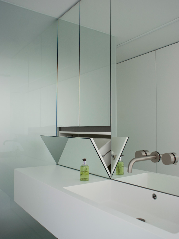 Modernes Duschbad mit flächenbündigen Schrankfronten, Mineralwerkstoff-Waschtisch, bodengleicher Dusche, weißer Wandfarbe, Betonboden und Wandwaschbecken in Berlin