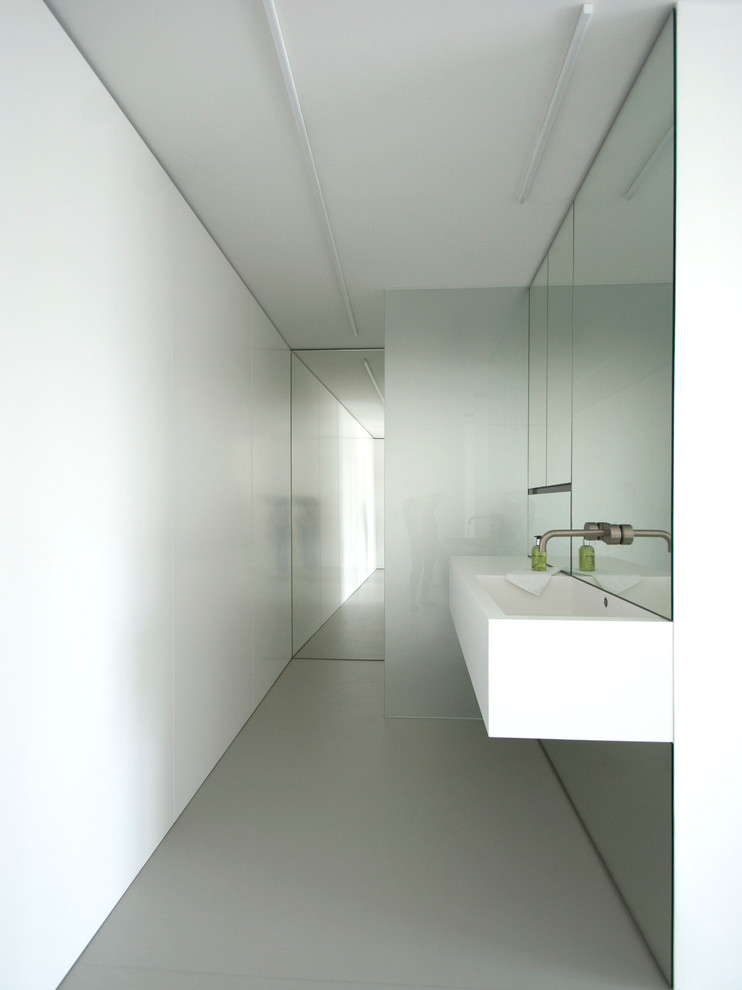 Foto de cuarto de baño moderno con ducha a ras de suelo, paredes blancas, suelo de cemento, aseo y ducha y lavabo suspendido