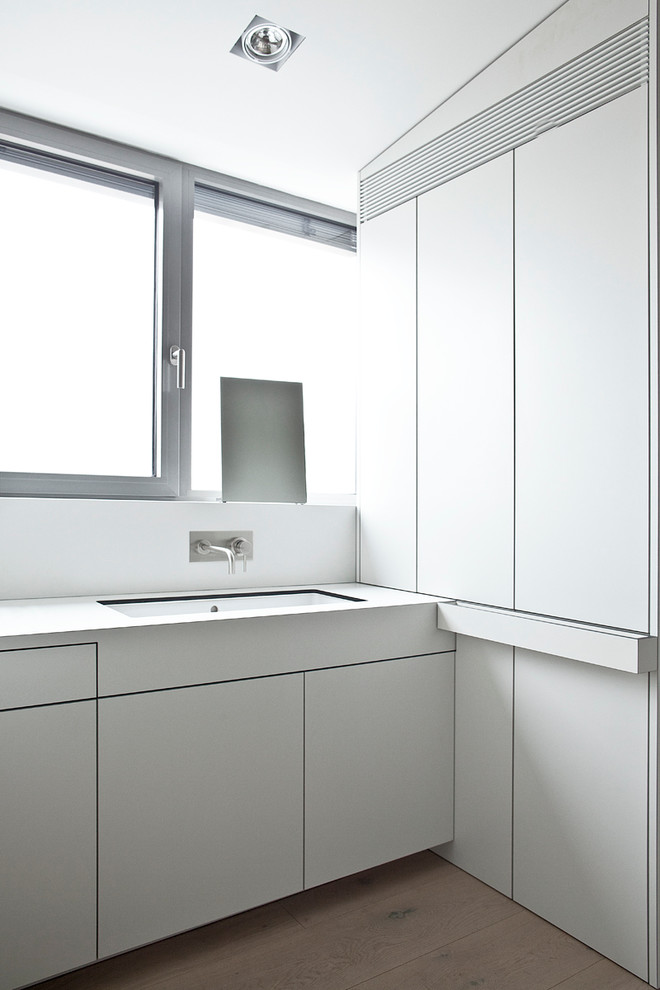 Modernes Badezimmer mit flächenbündigen Schrankfronten, bodengleicher Dusche, weißer Wandfarbe, Betonboden, Wandwaschbecken und Mineralwerkstoff-Waschtisch in Berlin