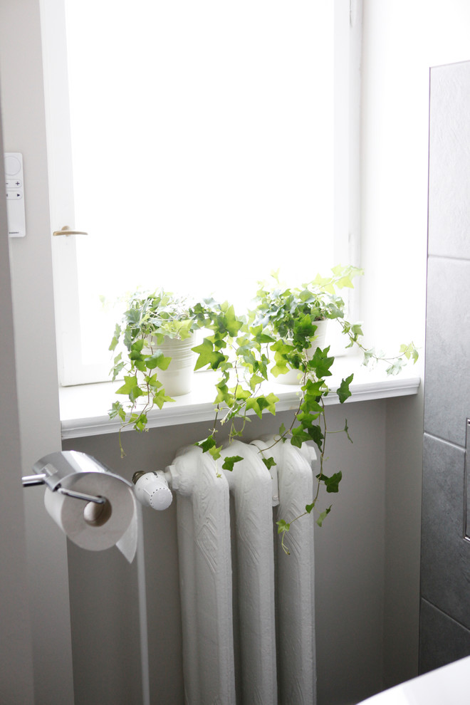 Inredning av ett mellanstort badrum med dusch, med en kantlös dusch, grå kakel, stenkakel, grå väggar, grått golv och dusch med gångjärnsdörr