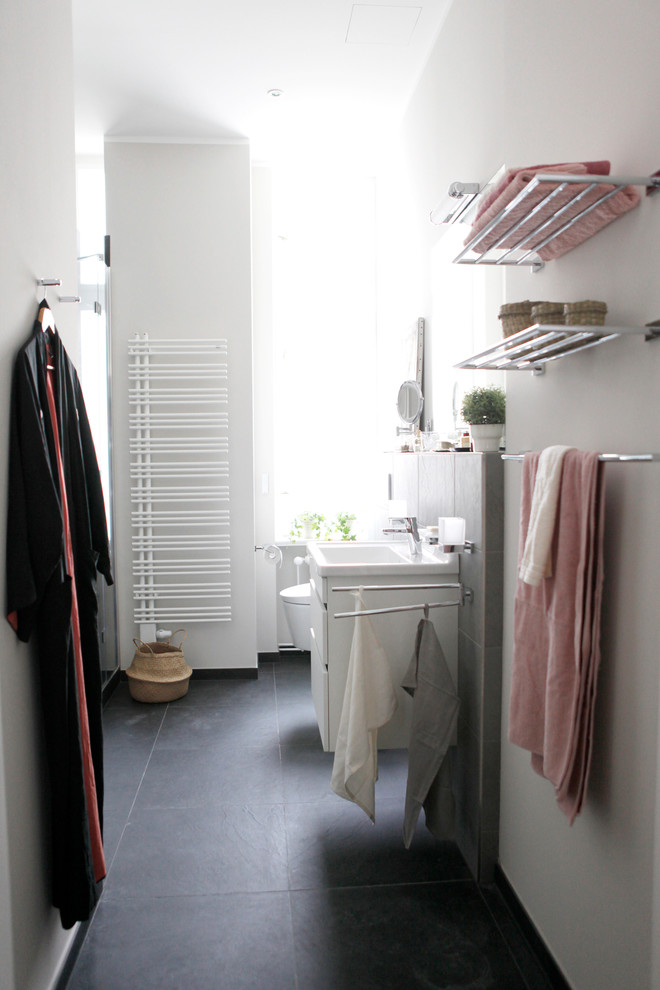 Стильный дизайн: ванная комната среднего размера с душем без бортиков, серой плиткой, каменной плиткой, серыми стенами, душевой кабиной, серым полом и душем с распашными дверями - последний тренд