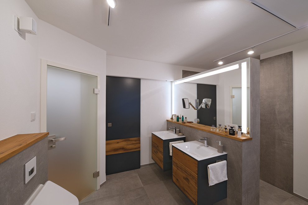 Idéer för mellanstora funkis badrum, med släta luckor, skåp i mellenmörkt trä, en öppen dusch, en vägghängd toalettstol, flerfärgad kakel, stenkakel, vita väggar, ett avlångt handfat och träbänkskiva