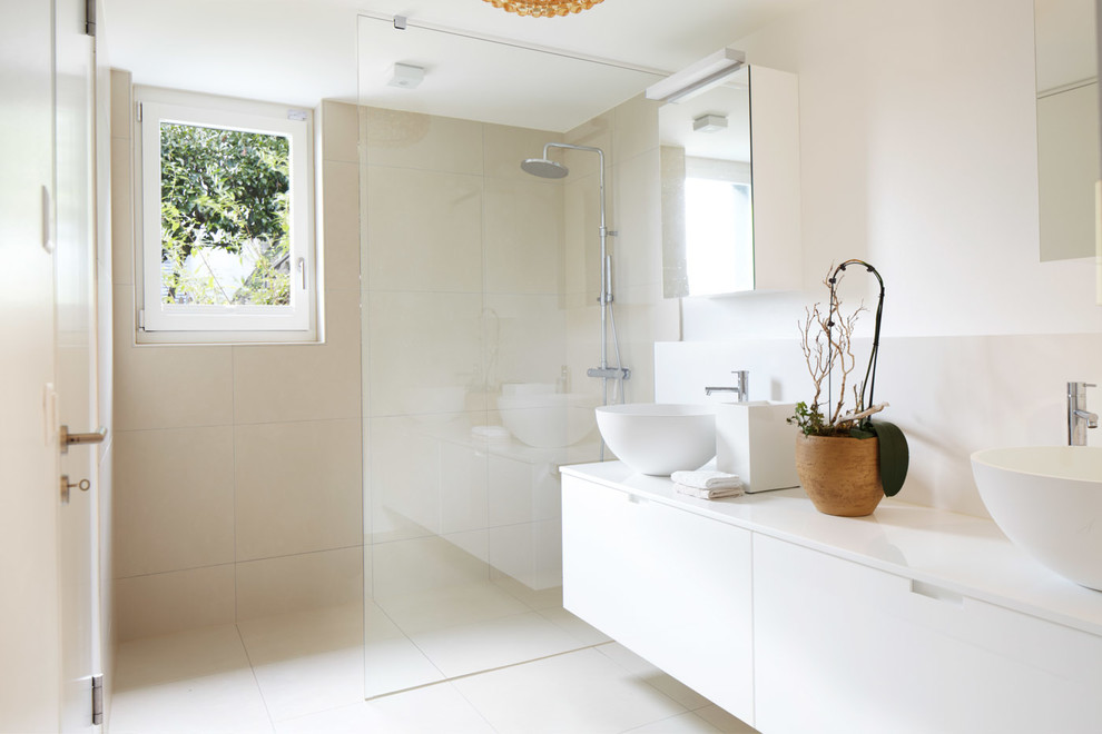 Foto på ett stort funkis badrum, med släta luckor, vita skåp, en kantlös dusch, beige kakel, stenkakel och vita väggar