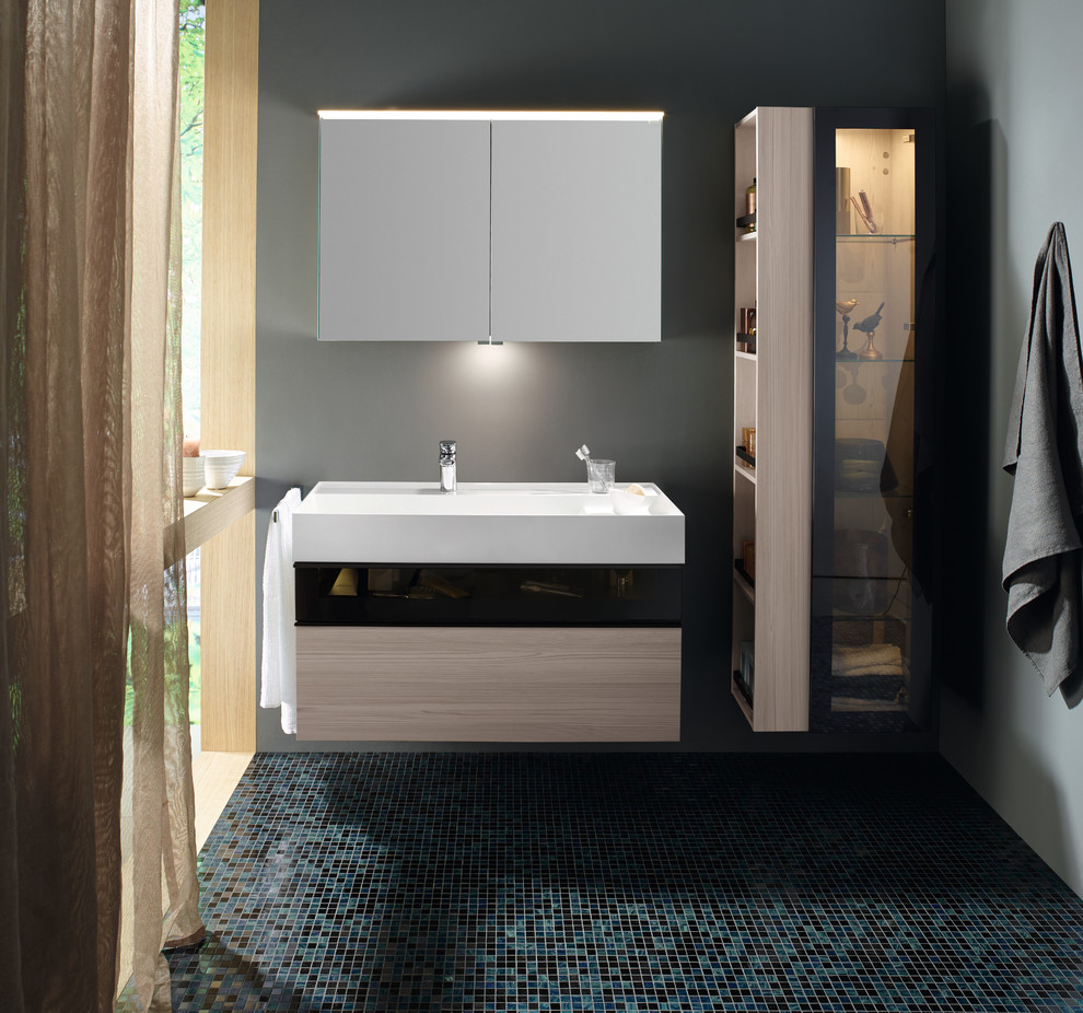 Inspiration pour une salle de bain design en bois clair de taille moyenne avec un placard à porte plane, une grande vasque et un plan de toilette en surface solide.