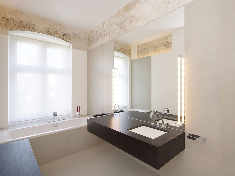 Design ideas for a medium sized contemporary bathroom in Berlin with a submerged sink, dark wood cabinets, an alcove bath, beige walls, flat-panel cabinets and grey tiles.