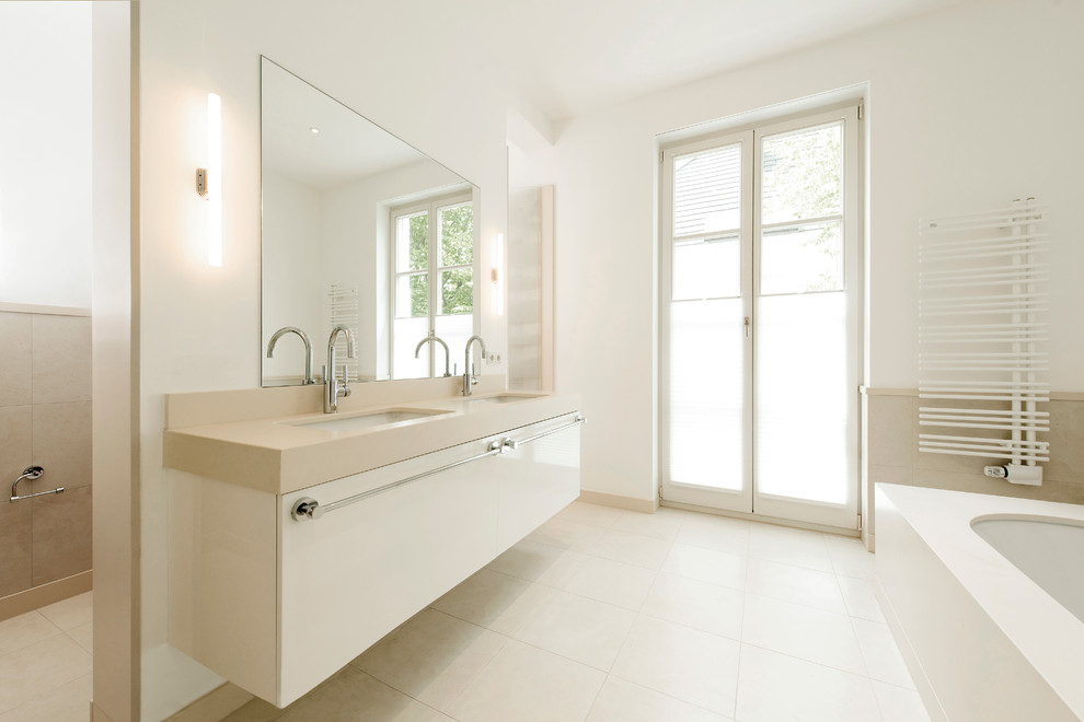 Diseño de cuarto de baño contemporáneo con armarios con paneles lisos, puertas de armario blancas, paredes blancas, suelo de piedra caliza, lavabo bajoencimera y ventanas