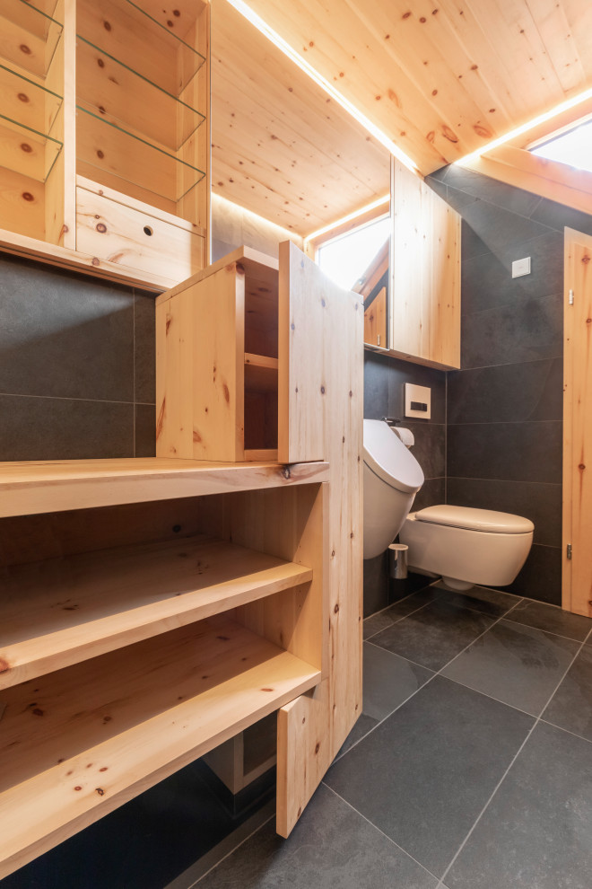 Idées déco pour une petite salle de bain contemporaine en bois clair avec un placard à porte plane, une douche à l'italienne, un bidet, un carrelage noir, du carrelage en ardoise, un mur noir, un sol en ardoise, une grande vasque, un plan de toilette en granite, un sol noir, aucune cabine, un plan de toilette marron, des toilettes cachées, meuble simple vasque, meuble-lavabo suspendu et un plafond en bois.